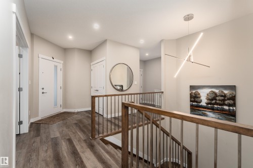 The property features wood-look flooring, a white entry door with a window, and a modern light fixture - 6193 Carr Road, Edmonton, AB - Indoor Photo Showing Other Room