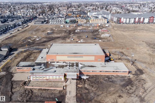 Aerial view of a large property featuring a building with a red brick exterior and a flat roof, surrounded by undeveloped land - 6193 Carr Road, Edmonton, AB - Outdoor With View