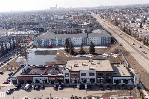 The property features a commercial building with several storefronts, a rooftop patio, and a parking lot - 6193 Carr Road, Edmonton, AB - Outdoor With View
