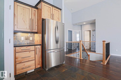 Kitchen featuring wooden cabinetry, a stainless steel refrigerator, and a tiled floor - 205 79 Street Sw, Edmonton, AB - Indoor