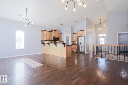 Open concept living area featuring dark hardwood floors, vaulted ceilings, and contemporary light fixtures - 205 79 Street Sw, Edmonton, AB - Indoor Photo Showing Kitchen