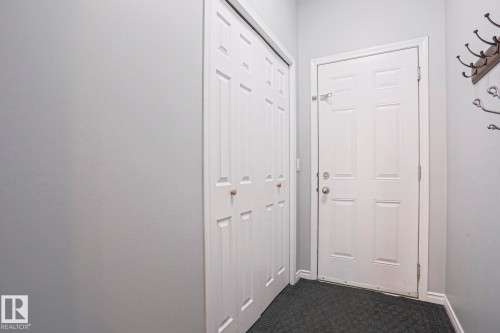Entryway featuring a white paneled door, bi-fold closet doors, and a dark carpeted floor - 205 79 Street Sw, Edmonton, AB - Indoor Photo Showing Other Room