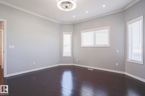 This spacious room features dark hardwood flooring, light grey walls, and white crown molding - 205 79 Street Sw, Edmonton, AB - Indoor Photo Showing Other Room
