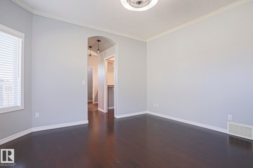 This room features dark wood flooring, light-colored walls, and crown molding - 205 79 Street Sw, Edmonton, AB - Indoor Photo Showing Other Room