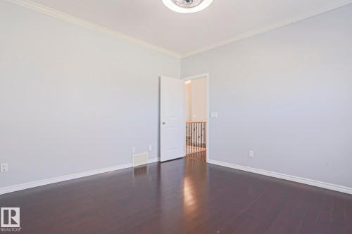 Spacious room featuring dark hardwood floors, light-colored walls, white trim, and a ceiling light fixture - 205 79 Street Sw, Edmonton, AB - Indoor Photo Showing Other Room