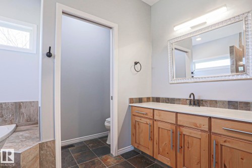 Bathroom featuring a vanity with wood cabinetry, a light-colored countertop, and a decorative framed mirror - 205 79 Street Sw, Edmonton, AB - Indoor