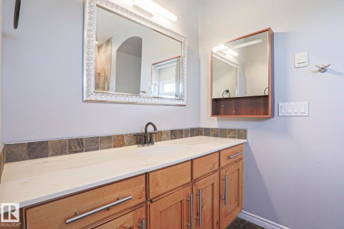 Bathroom vanity with a white countertop, an integrated sink, and wood cabinetry with silver hardware - 205 79 Street Sw, Edmonton, AB - Indoor Photo Showing Bathroom