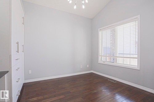 This room features dark hardwood flooring, light grey walls, and a large window with white blinds - 205 79 Street Sw, Edmonton, AB - Indoor Photo Showing Other Room