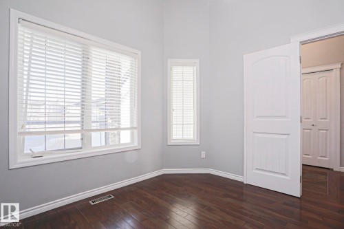 This room features hardwood floors, light gray walls, and two windows providing natural light - 205 79 Street Sw, Edmonton, AB - Indoor Photo Showing Other Room