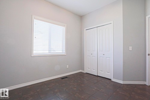 Room featuring tiled flooring, a window with blinds, and white bi-fold closet doors - 205 79 Street Sw, Edmonton, AB - Indoor Photo Showing Other Room