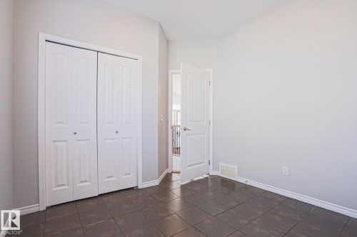 This room features tiled flooring, light-colored walls, and a bi-fold closet - 205 79 Street Sw, Edmonton, AB - Indoor Photo Showing Other Room