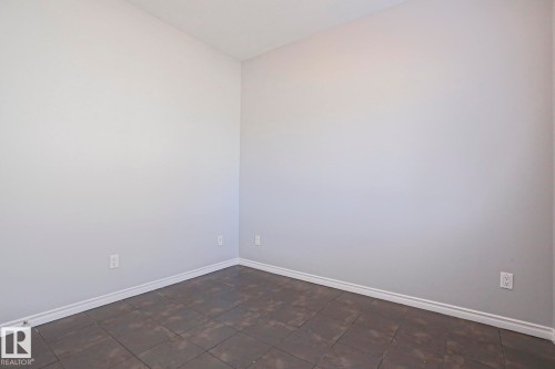 The room features light-colored walls, dark tiled flooring, and white baseboards - 205 79 Street Sw, Edmonton, AB - Indoor Photo Showing Other Room