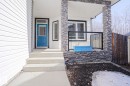 The property features a welcoming front entrance with a blue door, white siding, and stone veneer accents - 205 79 Street Sw, Edmonton, AB  - Outdoor With Exterior 