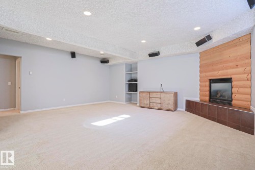 Spacious room featuring carpeting, recessed lighting, and a wood-paneled fireplace with a tiled hearth - 205 79 Street Sw, Edmonton, AB - Indoor With Fireplace