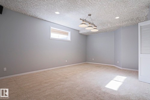 Spacious room featuring carpeted flooring, light grey walls, a window with a blind, and a modern ceiling light fixture - 205 79 Street Sw, Edmonton, AB - Indoor Photo Showing Other Room