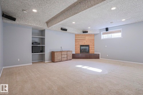 This room features light-colored carpeting, recessed lighting, and a window with blinds - 205 79 Street Sw, Edmonton, AB - Indoor With Fireplace