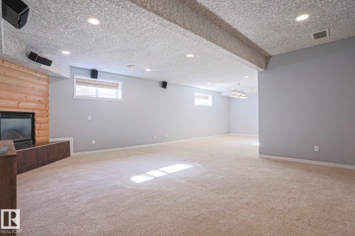 Spacious room featuring light-colored carpeting, recessed lighting, and a fireplace with a light wood surround - 205 79 Street Sw, Edmonton, AB - Indoor With Fireplace