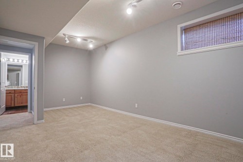 This versatile room features neutral carpeting, light grey walls, and track lighting for adjustable illumination - 205 79 Street Sw, Edmonton, AB - Indoor Photo Showing Other Room