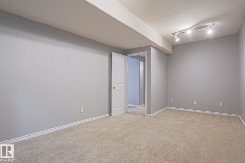The room features neutral-toned carpet, light gray walls, and white trim - 205 79 Street Sw, Edmonton, AB - Indoor Photo Showing Other Room