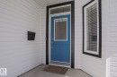The property features white siding, a blue entry door with a window, and a window with blinds - 205 79 Street Sw, Edmonton, AB  - Outdoor With Exterior 