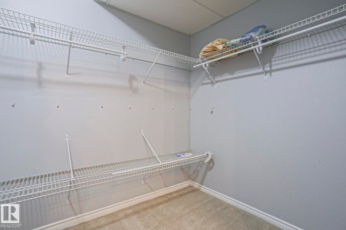 This room features light gray walls, a light-colored carpet, and white wire shelving, offering practical storage solutions - 205 79 Street Sw, Edmonton, AB - Indoor With Storage