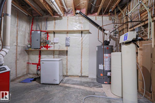 The property features a utility area with essential systems including a water heater, a water softener, and visible electrical panels - 205 79 Street Sw, Edmonton, AB - Indoor Photo Showing Basement