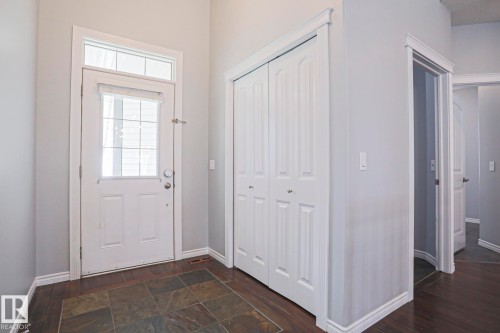 Entryway featuring a front door with an upper window and transom window, a bi-fold closet, and durable tile flooring - 205 79 Street Sw, Edmonton, AB - Indoor Photo Showing Other Room