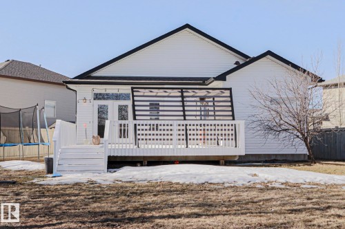 The property features a white exterior with a black roof, a white deck with railings and steps, and a double glass door entrance - 205 79 Street Sw, Edmonton, AB - Outdoor