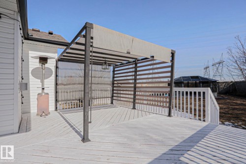 The property features a white wooden deck with a dark-framed pergola, complete with a retractable fabric canopy and privacy screens - 205 79 Street Sw, Edmonton, AB - Outdoor With Exterior