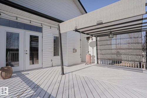 Spacious outdoor deck with white painted planks, featuring a white vinyl siding exterior, and French doors with an overhead transom window - 205 79 Street Sw, Edmonton, AB - Outdoor With Deck Patio Veranda With Exterior