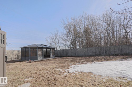 The property features an expansive backyard with a screened gazebo, a wooden fence, and mature trees lining the perimeter - 205 79 Street Sw, Edmonton, AB - Outdoor