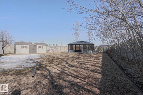 The property features a spacious backyard with a gazebo, two storage sheds, and a wooden fence - 205 79 Street Sw, Edmonton, AB - Outdoor