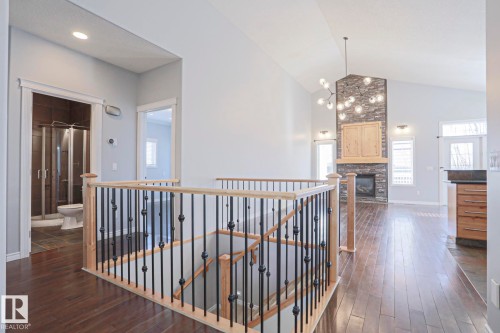 This property features rich hardwood flooring, a staircase with wrought iron balusters and natural wood handrails, and a vaulted ceiling in the living area - 205 79 Street Sw, Edmonton, AB - Indoor Photo Showing Other Room