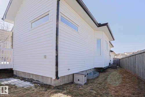 The property features white horizontal siding and a dark roofline, complemented by a white deck railing - 205 79 Street Sw, Edmonton, AB - Outdoor With Exterior
