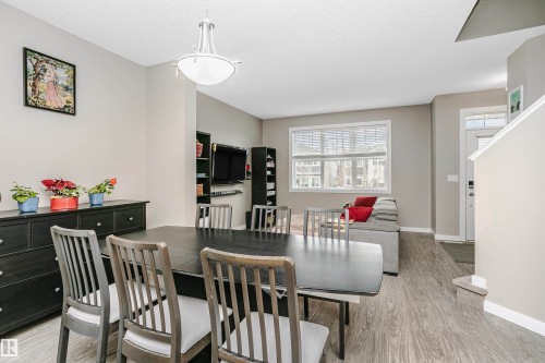 The dining area features a dark-toned dining table with matching chairs, complemented by a contemporary light fixture - 6116 Rosenthal Way, Edmonton, AB - Indoor Photo Showing Dining Room