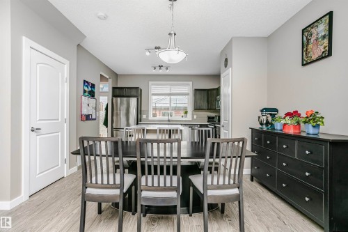 The dining area features light-toned flooring and a dark dining table with seating - 6116 Rosenthal Way, Edmonton, AB - Indoor Photo Showing Dining Room