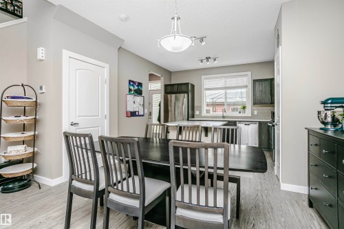 The property features an open concept kitchen and dining area, light grey flooring, and a window with blinds - 6116 Rosenthal Way, Edmonton, AB - Indoor Photo Showing Dining Room