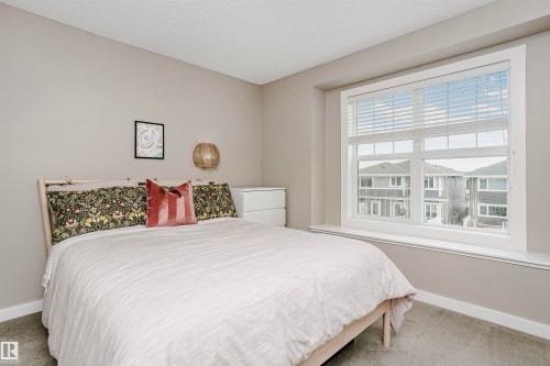 This room features a window with white blinds, a light-colored carpet, and walls painted in a neutral tone - 6116 Rosenthal Way, Edmonton, AB - Indoor Photo Showing Bedroom