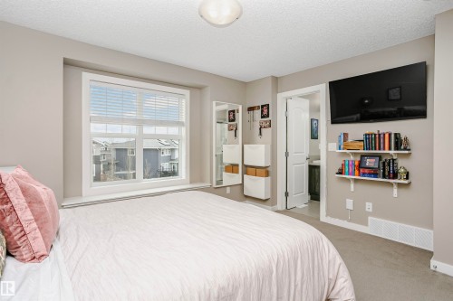 This room features neutral-toned walls and carpeting, a large window with blinds, and white trim - 6116 Rosenthal Way, Edmonton, AB - Indoor Photo Showing Bedroom