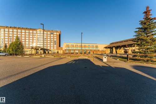 The property features a large parking area with lamp posts, and a building with "RIVERCREE" visible on its facade - 6116 Rosenthal Way, Edmonton, AB - Outdoor With Deck Patio Veranda