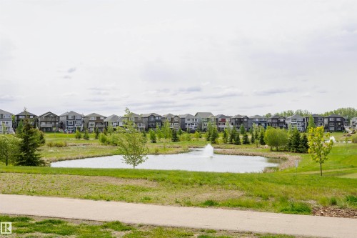 The property is situated in a community featuring a pond with a fountain, surrounded by green spaces and mature trees - 6116 Rosenthal Way, Edmonton, AB - Outdoor With View