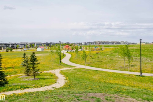 The property is situated within a community featuring a park with extensive green spaces, paved walking paths, and well-maintained trees - 6116 Rosenthal Way, Edmonton, AB - Outdoor With View