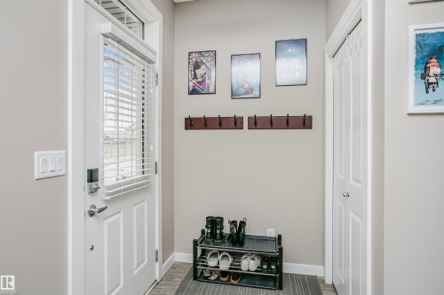 Entryway featuring light gray walls, a white front door with a window and white blinds, and a coat rack with multiple hooks - 6116 Rosenthal Way, Edmonton, AB - Indoor Photo Showing Other Room
