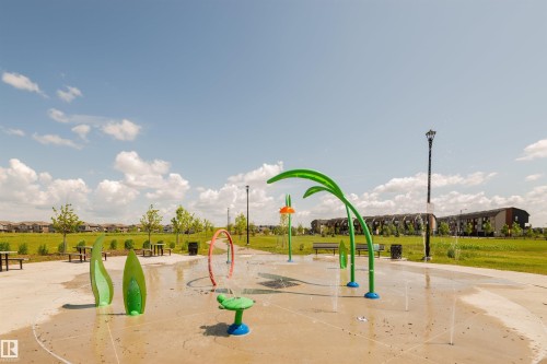 The community features a splash pad with various water play structures, surrounded by green spaces and paved pathways - 6116 Rosenthal Way, Edmonton, AB - Outdoor With View