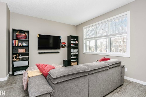 Living area featuring neutral-toned walls, a large window, and light wood-style flooring - 6116 Rosenthal Way, Edmonton, AB - Indoor