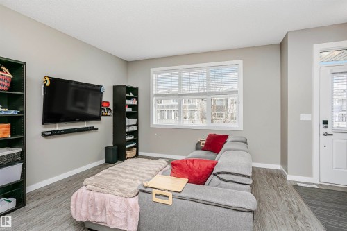 Living room featuring grey walls, hardwood style flooring, and a window with white blinds - 6116 Rosenthal Way, Edmonton, AB - Indoor