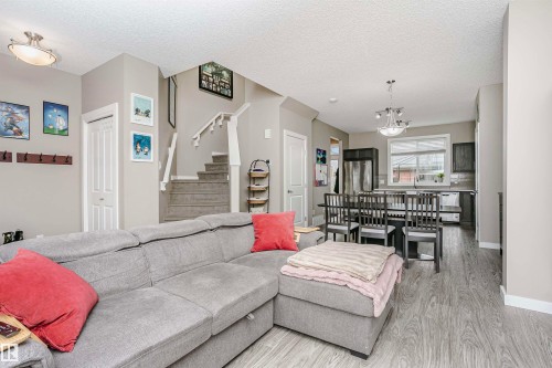 Open concept living area with light-toned walls, hardwood style flooring, and a carpeted staircase - 6116 Rosenthal Way, Edmonton, AB - Indoor Photo Showing Living Room