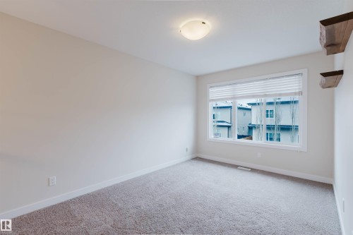 This room features light-colored walls and carpeting, a window with blinds, and a ceiling light fixture - 2878 Koshal Crescent, Edmonton, AB - Indoor Photo Showing Other Room