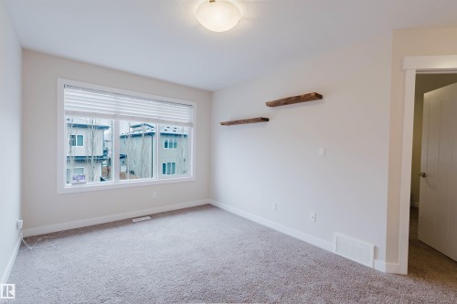 The room features light gray carpet flooring and white walls, complemented by a large window with white blinds - 2878 Koshal Crescent, Edmonton, AB - Indoor Photo Showing Other Room