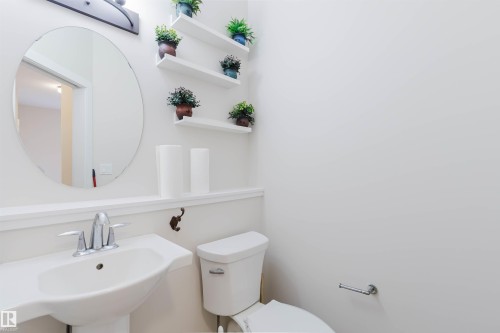 Powder room featuring a pedestal sink, an oval wall mirror, and a toilet - 2878 Koshal Crescent, Edmonton, AB - Indoor Photo Showing Bathroom